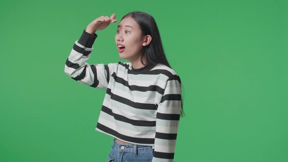 Side View Of Asian Woman Looking At Something While Standing In Front Of Green Screen Background