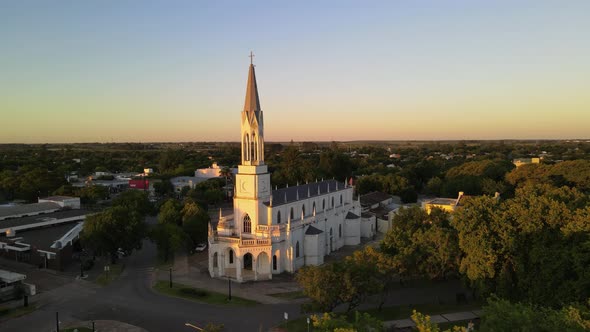 Aerial view orbiting around Virgen Niña catholic church in Villa Elisa town at golden hour