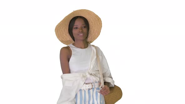 Relaxed African American Girl Walking Wearing a Straw Hat and a Bag on White Background