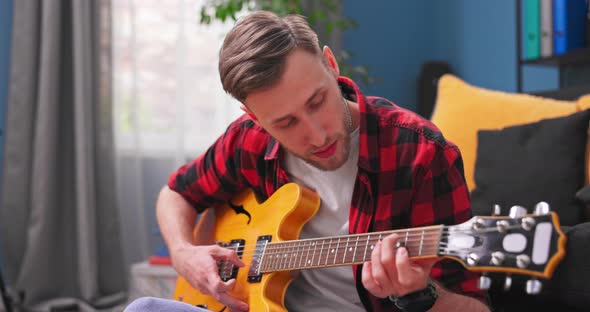 Man Playing Guitar in His Bedroom and Spending Time at Home Practicing