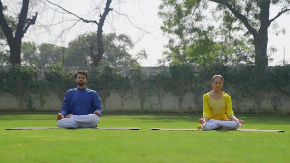 Lotus Yoga Pose or Padmasana is being done by an Indian couple in an Indian outfit