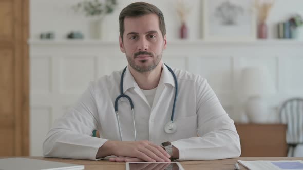 Serious Young Doctor Sitting in Clinic