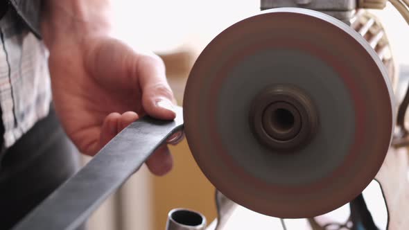 The Craftsman Is Sharpening the Edges of a Belt on a Special Machine