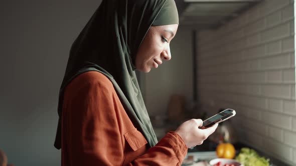 Handsome Muslim woman typing by phone