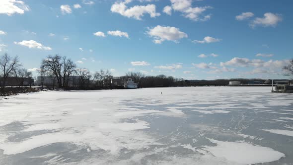 Snow and ice covered river in Wisconsin in winter. Sunny sky with clouds.