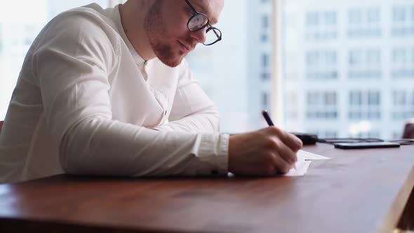 Handsome Young Man Wearing Stylish Eyeglasses Is Working with Paper Document