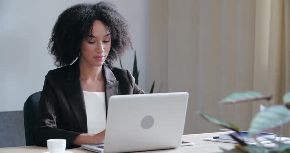 Serious African American Student Freelancer Wear Black Jacket Sitting at Desk at Home, Typing on