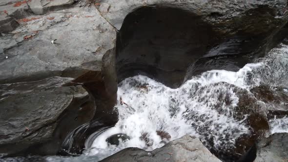 Slow motion shot of a small waterfall from the top. Shows the rock formations quite well.