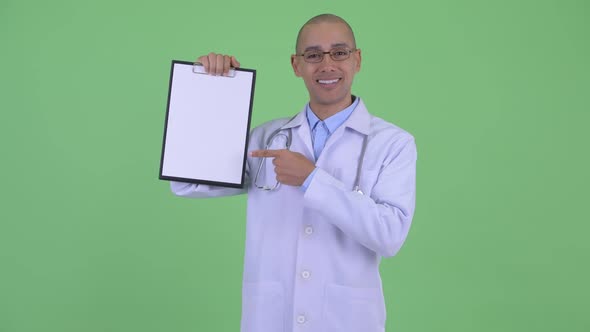 Happy Bald Multi Ethnic Man Doctor Showing Clipboard and Giving Thumbs Up