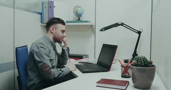 Office Worker, Sitting on His Desk Talking on Phone