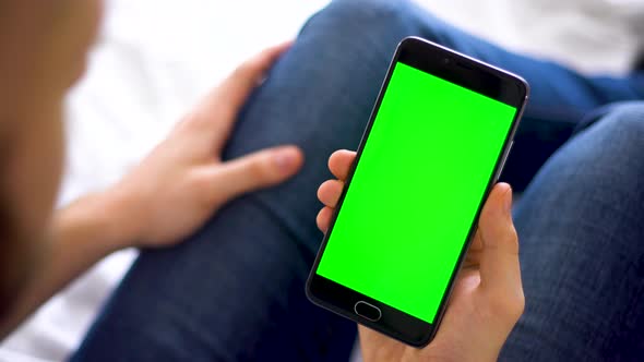 Black Smartphone with Green Screen for Chroma Key Compositing the Hands of a Man on Laptop