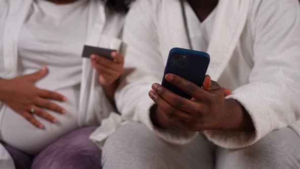 Unrecognizable African American Man Typing on Smartphone Touchscreen As Pregnant Woman Telling Web