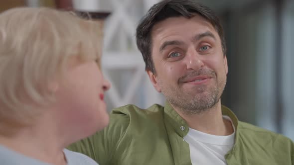 Portrait of Cheerful Handsome Adult Son Talking with Senior Mother Hugging Parent Smiling