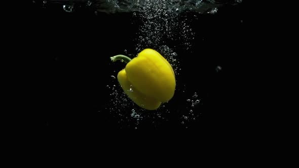 Yellow Bell Pepper Falling Into Water With Lot Of Air Bubbles Black Background