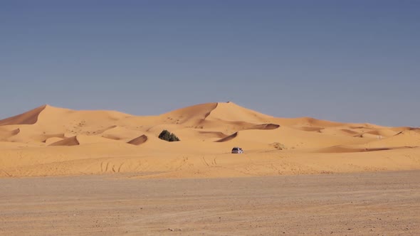 Car Driving Over Sand In Desert Landscape Of Merzouga