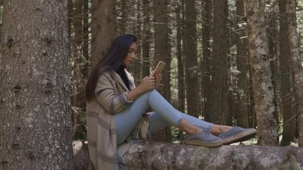 Attractive Woman Relax in Forest and Using Smartphone Outdoors