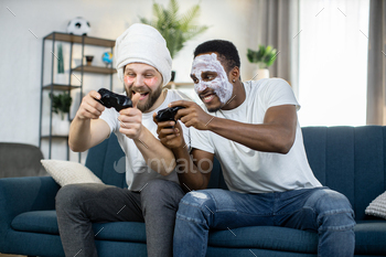 Multiethnic men doing skin care procedures, playing video games using joysticks