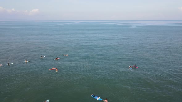 Aerial view of people surfing on waves with surfboards when vacation in Bali, Indonesia .