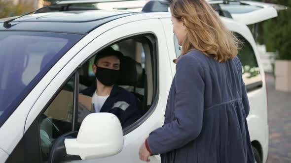 Delivery Man Wearing Uniform Protection Mask and Gloves Hand Over a Package to Customer on the Cargo