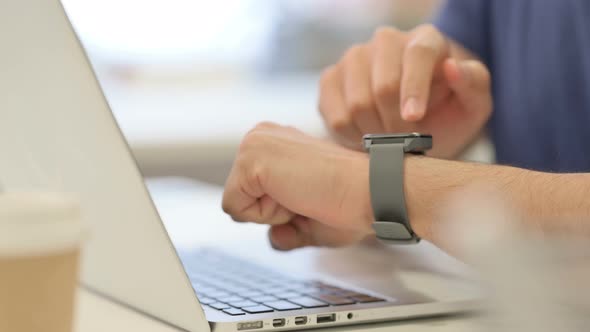 Close Up of Male Hands Using Smartwatch While Working on Laptop