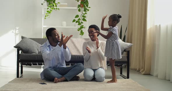 Active Little Girl Child Sings Song for Audience of Mom and Dad Sitting on Floor Shows Movements