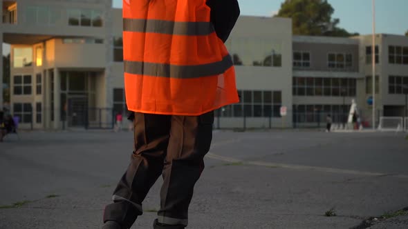Security Officer Holding Two-way Radio And Wearing Bright High-visibility Vest Standing In The Stree