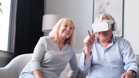Portrait of Elderly Couple Using Virtual Reality Glasses While Sitting in Living Room