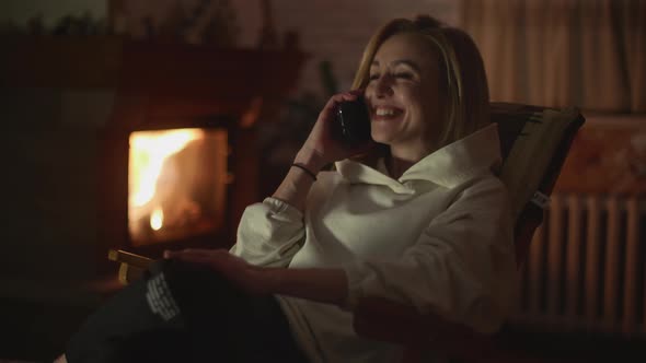 A Pretty Woman Having Phone Call and Smiling Near Fireplace