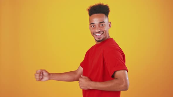 Playful African American Guy Moonwalking Into Shot and Keep Dancing Orange Studio Background