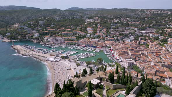 Flight over a historic castle and a port in Cassis town in Provence, France