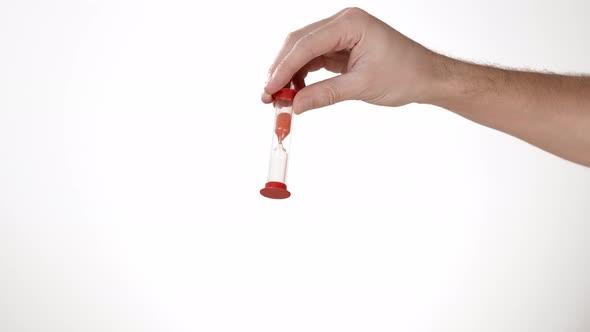 Time Begins. A Man's Hand on a White Background of Isolate Holds an Hourglass and Turns It Over