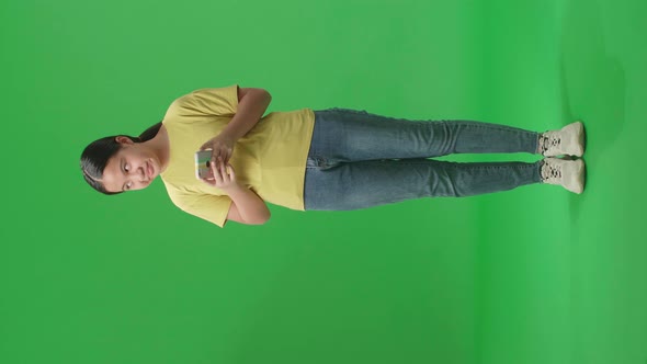 Full Body Of Asian Kid Girl Emotionally Flipping Something On The Phone In The Green Screen Studio