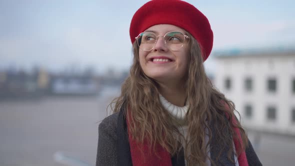 Portrait of Stylish Joyful Young Caucasian Woman in Eyeglasses and Beret Looking Around Smiling