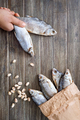 Hand holds several dried carp. Salty fish and pistachios on a wooden background - PhotoDune Item for Sale