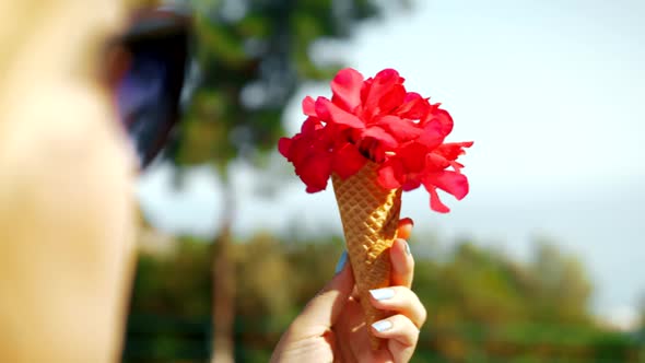 Woman Holding Red Flowers in Waffle Cone