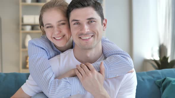 Smiling Young Couple in Hug Looking at Camera