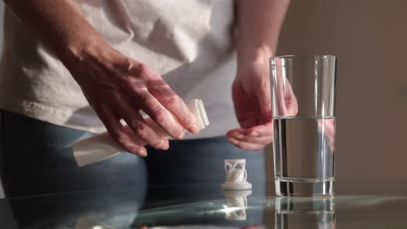 A Woman Puts an Effervescent Tablet Vitamin C in a Glass of Clean Water