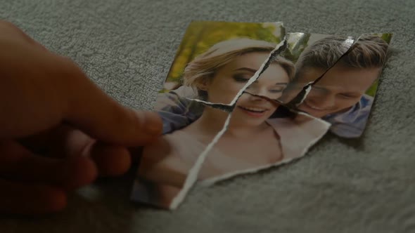 Male Hands Connecting Tearing Pieces of Photo With His Girlfriend Yearning