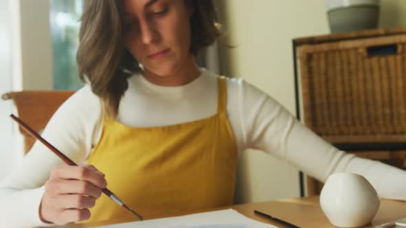 Caucasian woman with brown hair painting at home