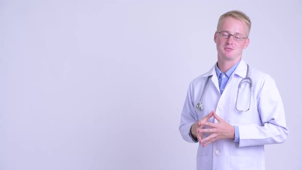 Happy Young Blonde Man Doctor Talking and Touching Something