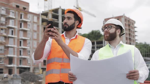 The Builder and Architect on Construction Site Photographing with Smartphone
