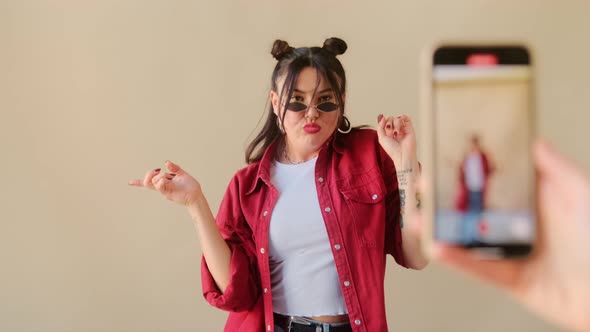 Young stylish trendy woman recording dance video for social media account on phone.