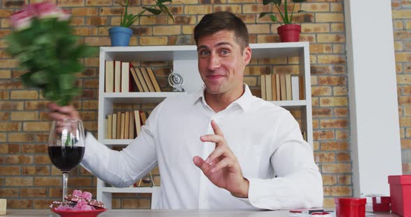 Caucasian man making video call presenting bunch of flowers blowing kiss and smiling