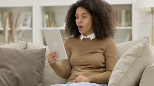 Video Chat on Tablet By Young African Woman on Sofa