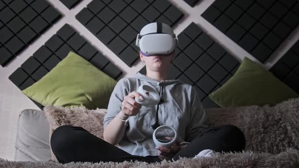 Young Woman in Virtual Reality Helmet Sitting on Sofa and Move Hands at Home