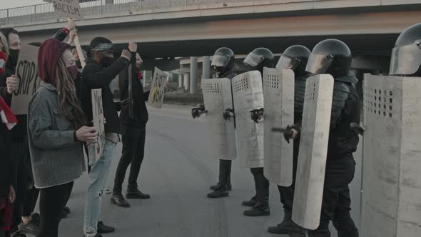 Youth with Signs Protesting before Riot Police with Shields