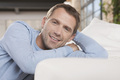 Germany, Cologne, Man sitting by sofa, smiling, portrait - PhotoDune Item for Sale