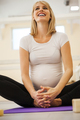 Smiling pregnant woman sitting on gym mat - PhotoDune Item for Sale