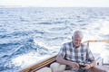 Senior man on a boat trip looking at cell phone - PhotoDune Item for Sale