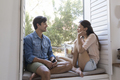 Smiling young couple sitting on windowsill - PhotoDune Item for Sale